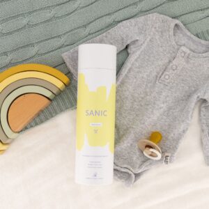 Sanic Baby fresh bottle flat lay with grey babygrow, wooden rainbow and a pacifier. 